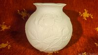 Front angle showing vase shape and raised rose pattern in white bisque porcelain.