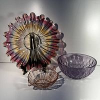 Three glass items: a large starburst shaped Federal Glass Celestial plate/dish, a purple diamond patterned Anchor Hocking bowl, and a pink heart-shaped Anchor Hocking depression glass jelly dish.