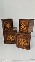 Four wooden canisters arranged in a stack, showing floral design and dovetail joints