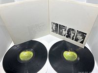 Double LP vinyl records with gatefold sleeve open, showing the Beatles members' black and white photo strip inside and green Apple Records label on the records.