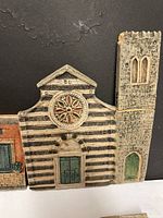 Close-up of the striped church facade showing rose window and tall tower with green door, part of the ceramic village set.