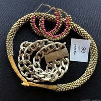 All four pieces of jewelry shown together on a black background: beaded choker, heavy link bracelet, colorful beaded hoop earrings.