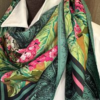 Close-up detail of the scarf's fabric and vibrant floral and paisley print, showing hand rolled edges and twill silk texture.