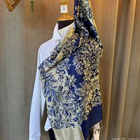 Blue shawl with intricate gold floral embroidery draped over a mannequin wearing a white shirt, showing the full size and pattern.