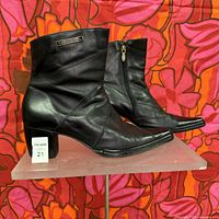 Profile side view of the boots showing black leather-like material, block heel and Harley Davidson metal logo