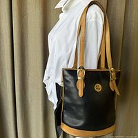 Full view of navy blue textured leather shoulder tote with tan leather trim and adjustable straps on mannequin