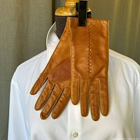 Front and back view of tan horsehide women's gloves hung on a shirt-style display.