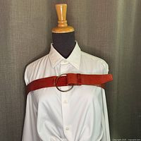 Front view of red leather belt on mannequin, displaying the single O-ring closure and texture.