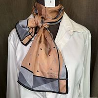 Silk scarf tied around mannequin neck showing color, pattern, and fabric drape.