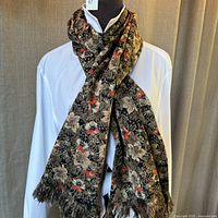 Brown floral silk blend scarf styled on a mannequin with a white shirt backdrop, showing the floral pattern and light fringe edges.