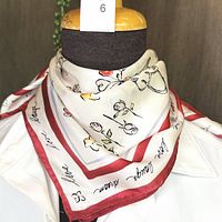 Silk square scarf displayed on mannequin neck showing burgundy border and hand-drawn style prints with words 'live love laugh dance'.