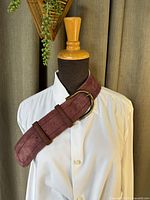 Full view of reddish suede belt displayed on mannequin with white shirt, showing texture and belt style.
