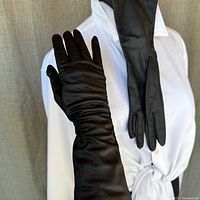 Front view of both black long evening gloves modeled on a white mannequin torso, showing full length and smooth texture.