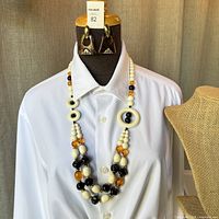 Full view of necklace and earrings displayed on mannequin with white shirt