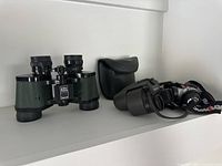Shelf photo showing both pairs of binoculars and Rayovac headlamp together