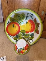 Top-down view showing full pattern of large and small enamel bowls with fruit designs.