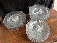 Full view of two stacks of clear pressed glass dessert plates, showing difference in size and design details