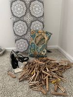 Close-up photo showing General Electric travel iron, wooden clothespins scattered and the decorative clothespin bag on carpeted floor