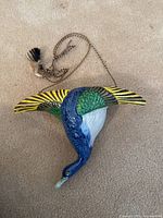 Full view of the ceramic wall vase in form of a flying goose with hanging chain and tassel