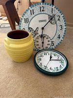 Grouped photo showing all three items: yellow pottery urn, outdoor thermometer clock with butterfly design, and green ivy wall clock.