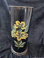 Front view of black tole umbrella stand showing full flower design on cylindrical body.