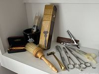 Photo showing Sears Barber Duster brush in original box, wooden brush, black shaving mug, classic razors and scissors.