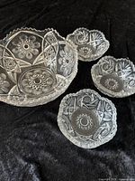 Photo showing entire set of one large and three smaller pressed glass bowls on black background