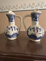 Front view of both ceramic oil and vinegar bottles, showing the blue and white Willow pattern design and lids