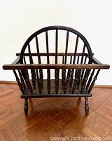 Front view of the vintage Windsor style wooden magazine rack, showing center spindles and rounded handle.