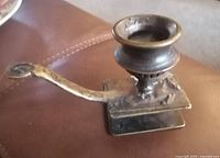 Side view of the antique brass candle stick holder showing the horse figure and elongated handle.