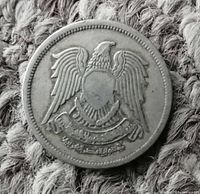 Obverse of silver coin showing Egyptian national emblem eagle with shield and Arabic inscription banner below.