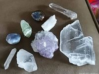 Top down view of natural crystals including clear quartz points, amethyst cluster, agate stones, and a large rough clear chunk.