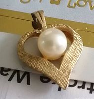 Front view of heart-shaped pendant showing textured finish and centered pearl