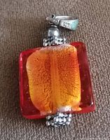 Close-up image showing square red lampwork glass pendant with orange foil interior and 925 silver bail and silver bead accents.