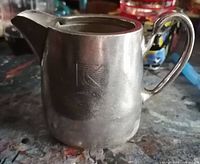 Side view of the small silver plate creamer pitcher displaying the CP Rail logo.