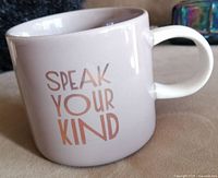 Photo of the mug side showing the phrase 'Speak Your Mind' in muted pink text on a light purple background.