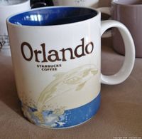 Starbucks Orlando mug with manatee design and blue rim, showing city name and Starbucks Coffee branding.