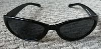Front view of black oval Steve Madden sunglasses on textured surface