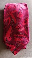 Photo of a red silk tie with abstract black and pink/red calligraphy-like designs