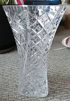 Large vintage cut crystal vase featuring a diamond lattice pattern, flared at the top, photographed on carpet floor.