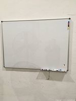 Front view of one whiteboard hanging on wall with marker tray attached at bottom
