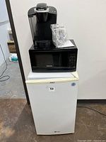 Microwave, fridge, and coffee maker stacked, showing overall lot items