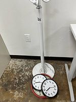 Photo of the round white marble base with three round clocks placed on the floor near it, showing the size and style of the clocks and base
