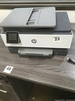 Front and top view of HP OfficeJet Pro 8035e printer showing touchscreen display, paper feeder and output tray.