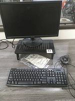 Front view of Asus monitor on metal riser with Logitech keyboard and wired mouse on desk