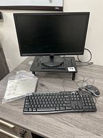 Front view of Asus monitor on metal riser with Logitech keyboard, mouse and Intel NUC box on tabletop