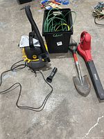 Photo of Stinger wet/dry shopvac with attached hose and power cord, black container holding green and yellow extension cords, short shovel with orange handle grip, and red Craftsman blower.