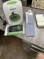 Full view of the Upunch HN3000 time clock, wall rack for cards, pack of time cards, manual, and key set on a table.