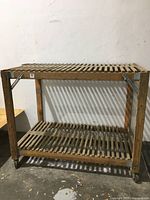 Front view of wood rolling cart showing two ventilated slatted shelves with some broken slats and metal corner reinforcements