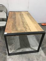 Full view of rectangular wood and black metal table showing top surface and frame.